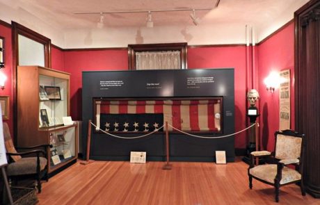 a room of a historical museum displaying the lincoln flag behind a roped off section